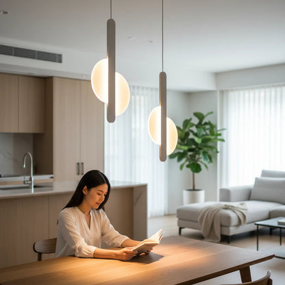 Lysverden minimalist white pendant lamp with opal acrylic orb hanging above a woman reading at a wooden dining table.