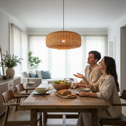 Lysverden handwoven natural rattan drum pendant light hanging over a wooden dining table with a couple in a bright room