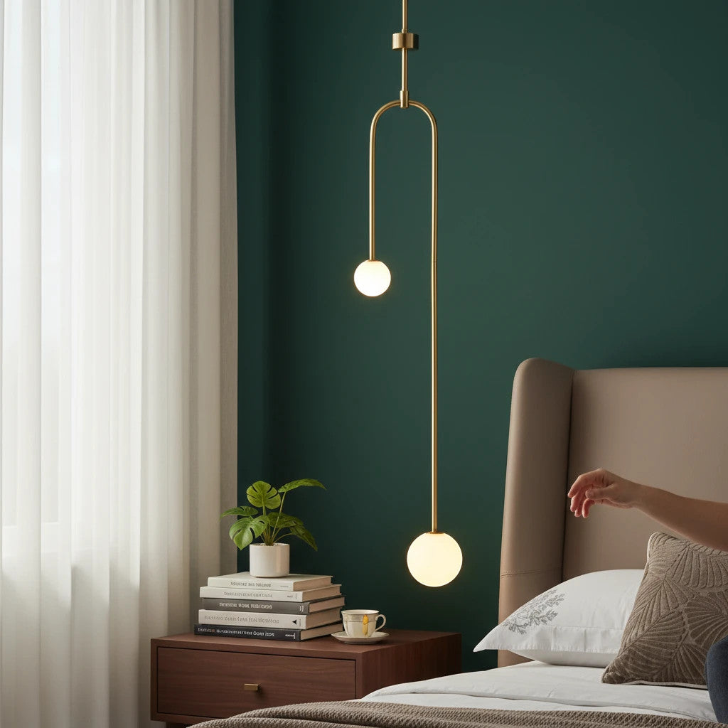 Lysverden minimalist pendant lamp with opal glass globes and a slim brass rod hanging over a bedroom nightstand.