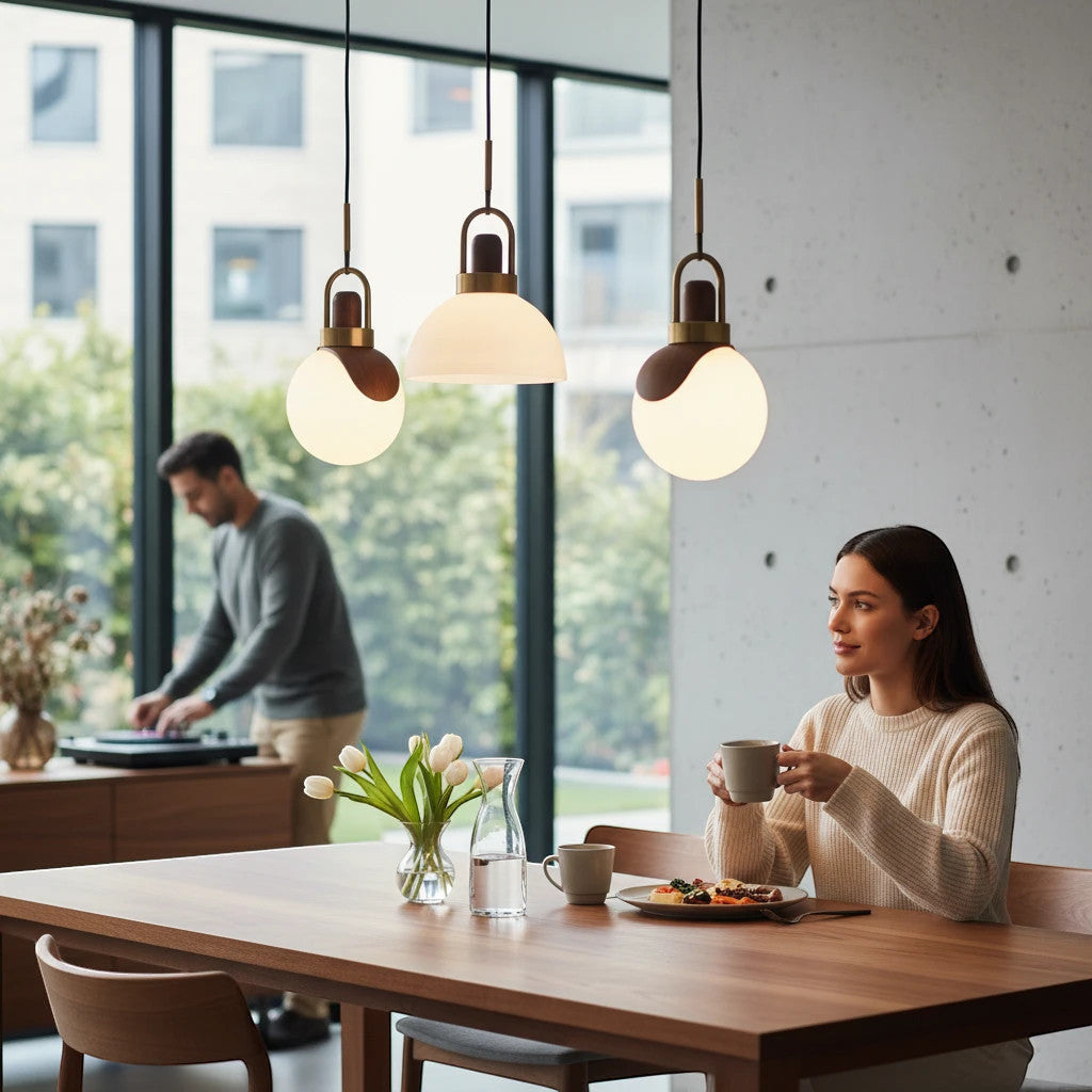 Lysverden opalglass pendant lights with brass and wood accents hanging over a dining table in a modern home