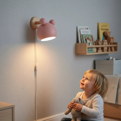 Lysverden pink Macaron wall lamp with wooden detail illuminating a child sitting in a cozy bedroom