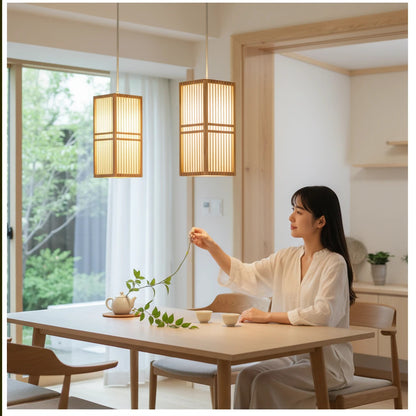 Lysverden Japanese-style rattan pendant lights hanging over a minimalist dining table with a woman in a bright room.