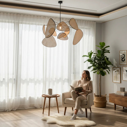 Lysverden sculptural rattan leaf pendant light hanging in a bright, modern living room with a woman reading nearby.