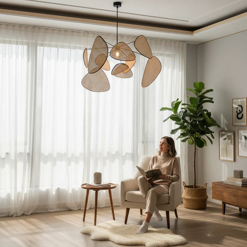 Lysverden sculptural rattan leaf pendant light hanging in a bright, modern living room with a woman reading nearby.
