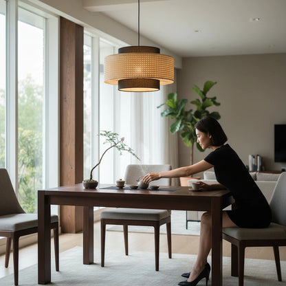 Lysverden round rattan pendant light with dark wood frame hanging over a dining table in a Japandi style room.