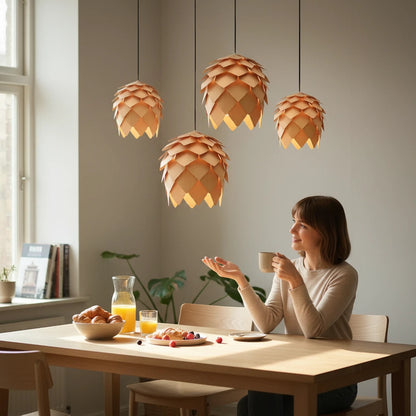 Lysverden rattan pendant lamps with pinecone-inspired design hanging over a woman sitting at a wooden dining table.