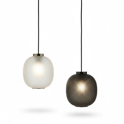 Lysverden runde riflede glasskulependler i hvit og sort med elegante metalldetaljer og varmt lys.