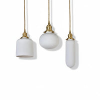Lysverden RILLE pendant lamps in white ribbed opal glass with brass details in three different shapes.