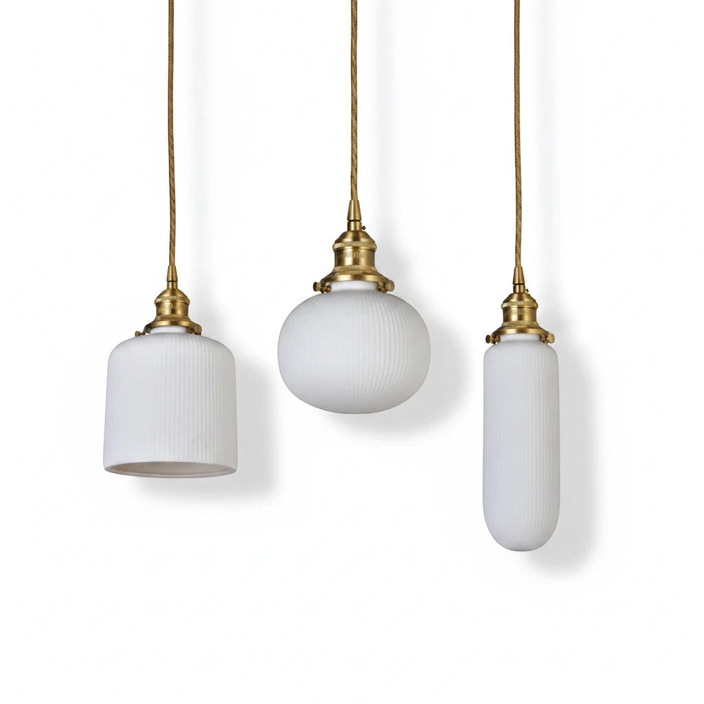 Lysverden RILLE pendant lights in white ribbed opal glass with brass details hanging in three different shapes.