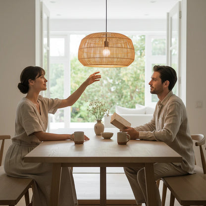 Lysverden round rattan drum pendant light hanging over a wooden dining table with a couple in a bright home interior