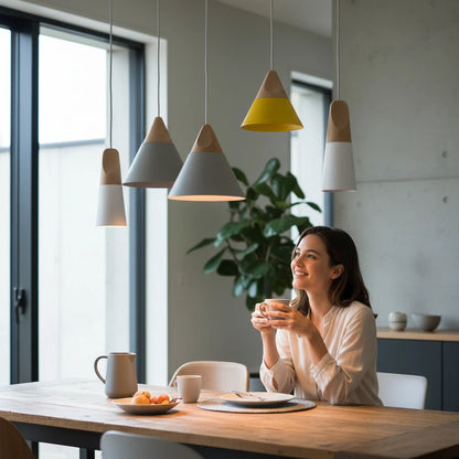 Lysverden Skråpendel pendant lights in various colors with wooden tops hanging over a dining table with a woman.