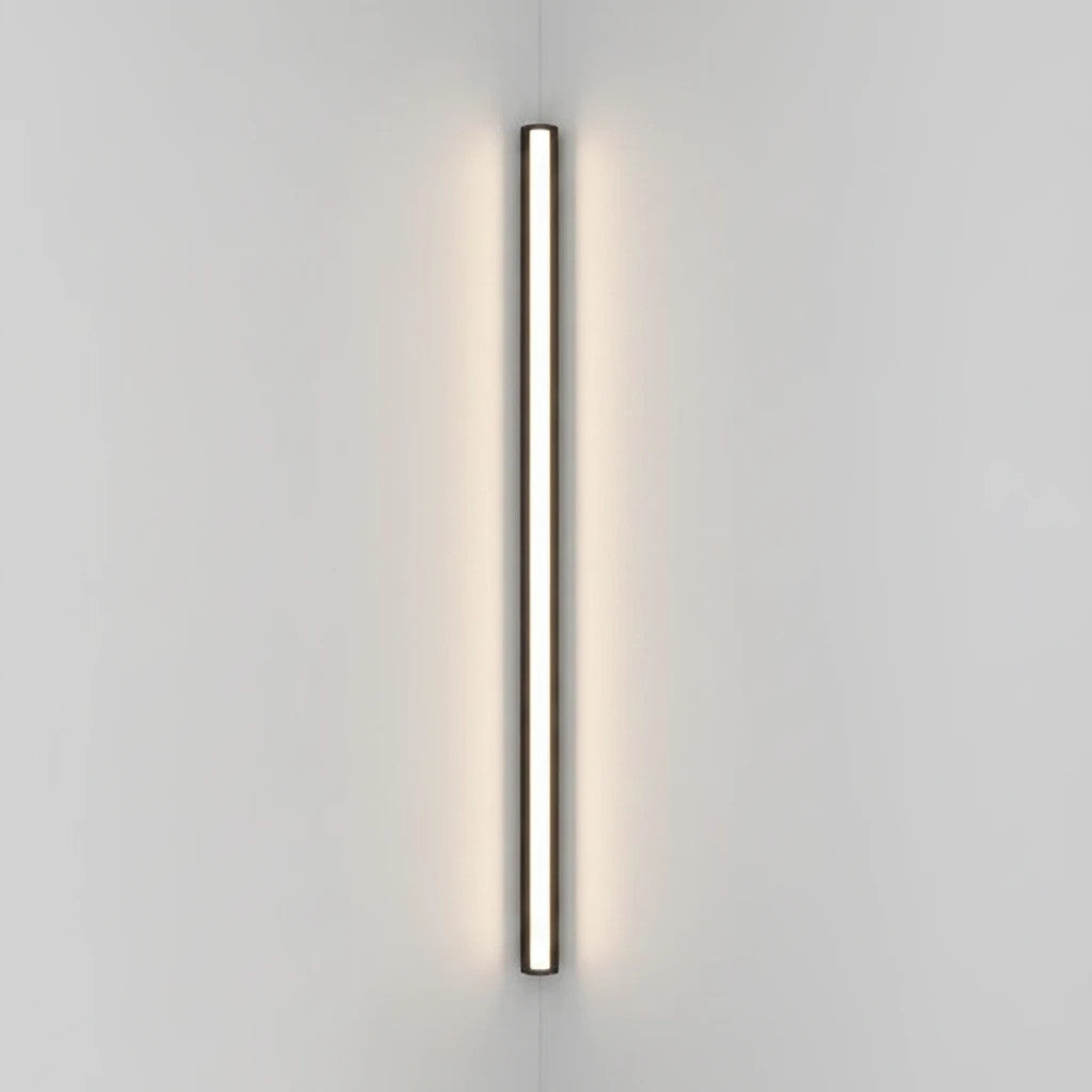 Lysverden minimalistisk sort lineær LED-vegglampe montert vertikalt på en hvit vegg med varmt diffust lys.