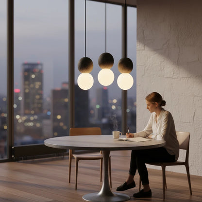 Lysverden Steinpendel pendant lights with textured stone spheres and opal glass globes hanging over a dining table.