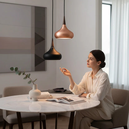 Lysverden teardrop pendant lamps in black and copper metal with wood accents hanging over a marble dining table