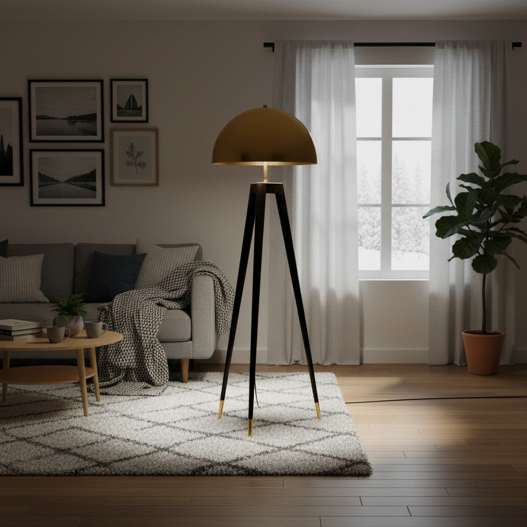 Lysverden tripod floor lamp with a gold brass dome shade and slim black legs in a modern living room setting.