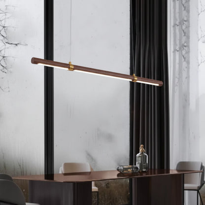 Lysverden linear LED pendant light in walnut wood with gold accents hanging over a modern dining table