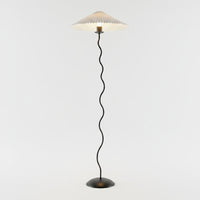 Lysverden sculptural floor lamp with a black wavy stem and a pleated white disc shade on a round base.