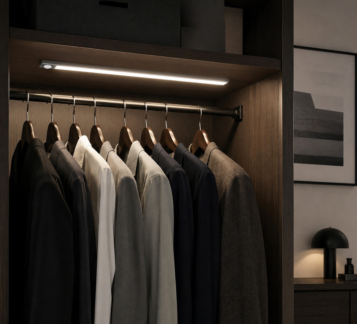 Lysverden wireless LED cabinet light with motion sensor mounted inside a dark wooden wardrobe illuminating clothes.