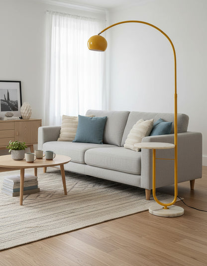 Lysverden yellow arched floor lamp with a stone base and glass shade standing next to a grey sofa in a living room